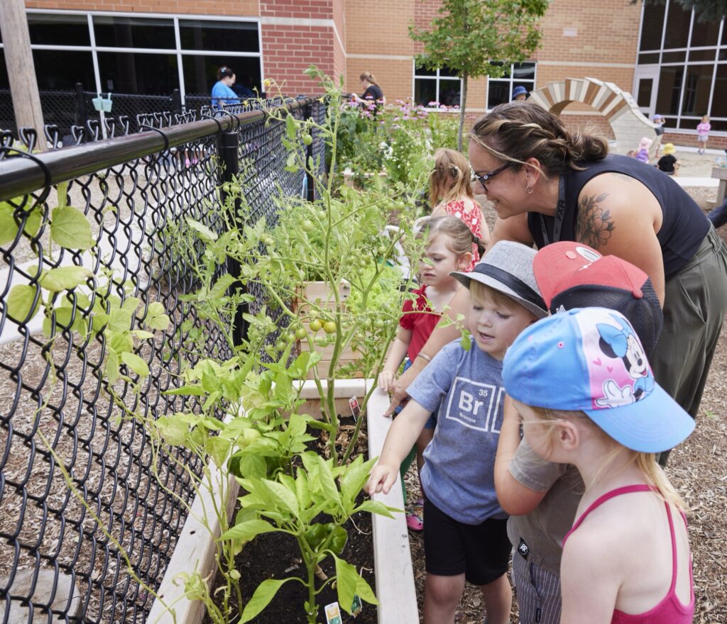 Group of small children learning about gardening from an adult