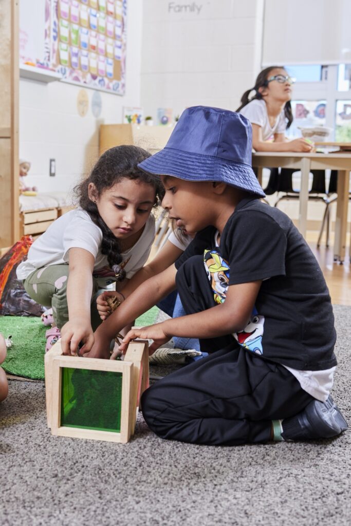 Two small children playing with wooden colourful toys