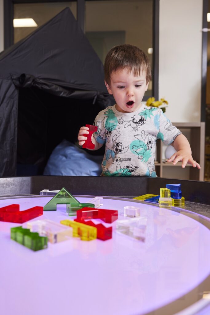 Young boy playing with colourful plastic blocks