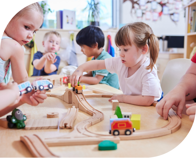 A group of small children playing with wooden cars on a wooden track