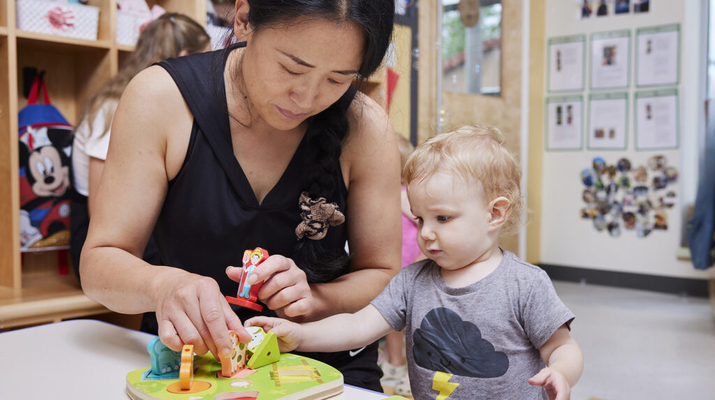 A woman showing toddler how to build a wooden puzzle